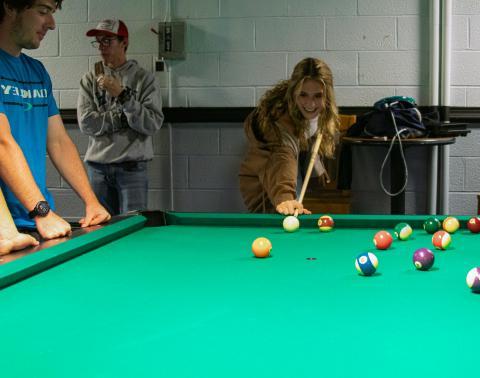 Student playing billiards.