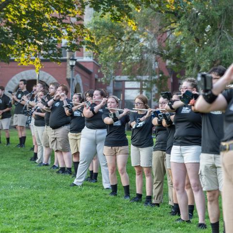 UNH band lined up playing instruments outside.